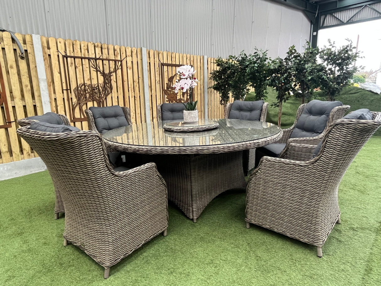 A Belgrade Deluxe Rattan Dining Set displayed outdoors, consisting of eight chairs around a circular table with glass top and a lazy Susan.