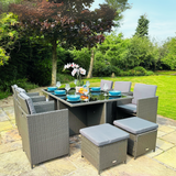 Outdoor patio set with table and chairs on a paved area with greenery in the background