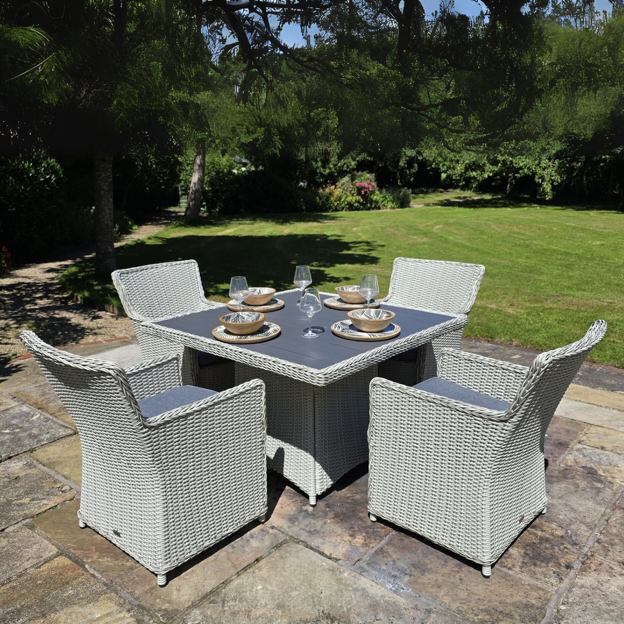 Outdoor patio set with a table and four chairs on a stone patio.