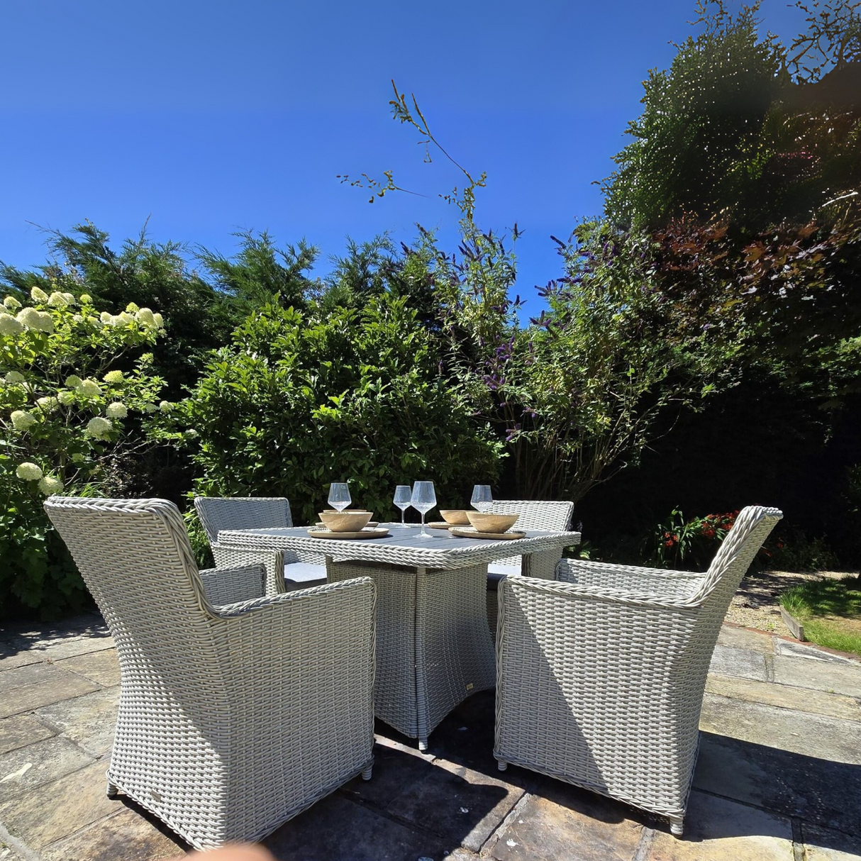 Outdoor patio set with table and chairs in a garden setting