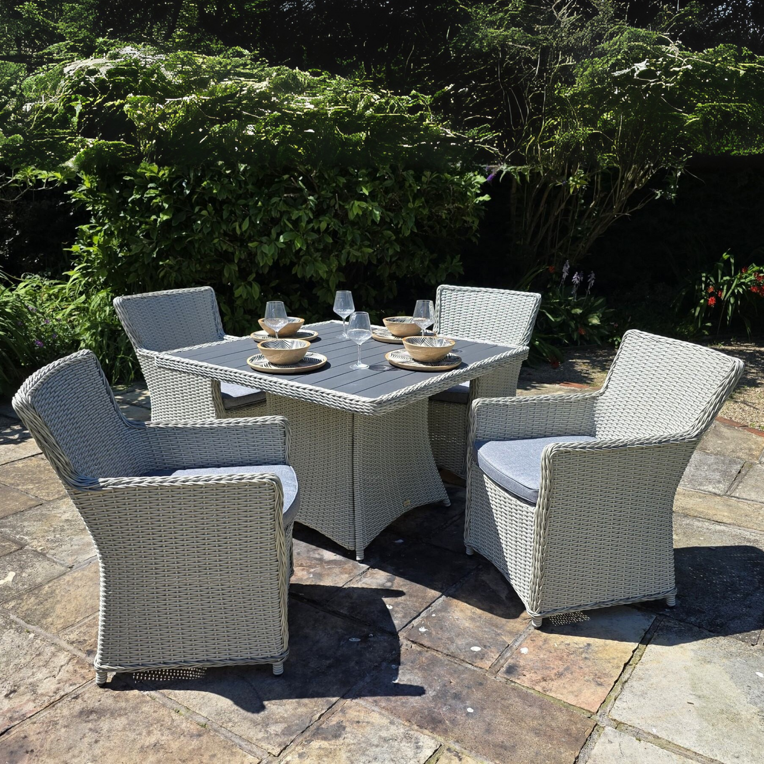 Outdoor patio set with a table and four chairs on a stone patio.