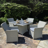 Outdoor patio set with a table and four chairs on a stone patio.