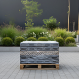 Stack of pallets with wrapped items on a paved area with greenery in the background