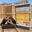 Packaging of Lovely Logs hardwood briquettes with logs on a wooden surface.