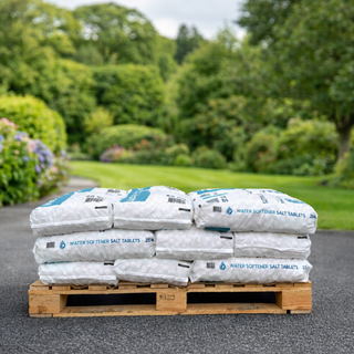 Stack of water softener salt tablets on a wooden pallet with a garden background