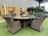 A Belgrade Deluxe Rattan Dining Set displayed outdoors, consisting of eight chairs around a circular table with glass top and a lazy Susan.