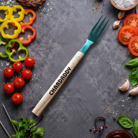 Fork with 'CHARDADDY' branding surrounded by vegetables on a dark surface