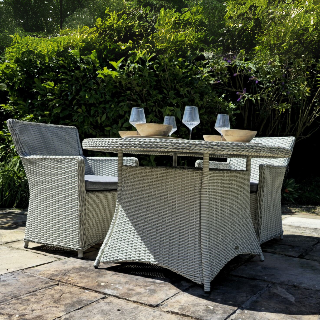 Outdoor patio set with wicker chairs and table in a garden setting